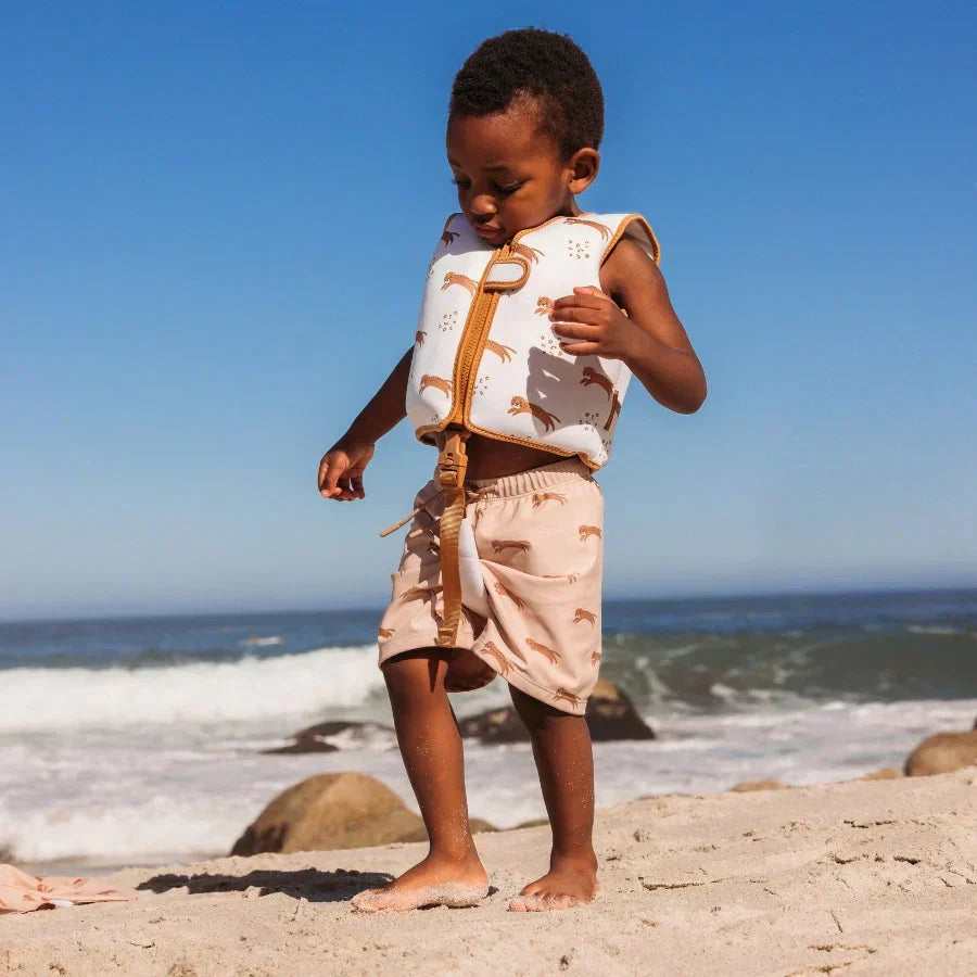 child on beach with swim vest and swim shorts