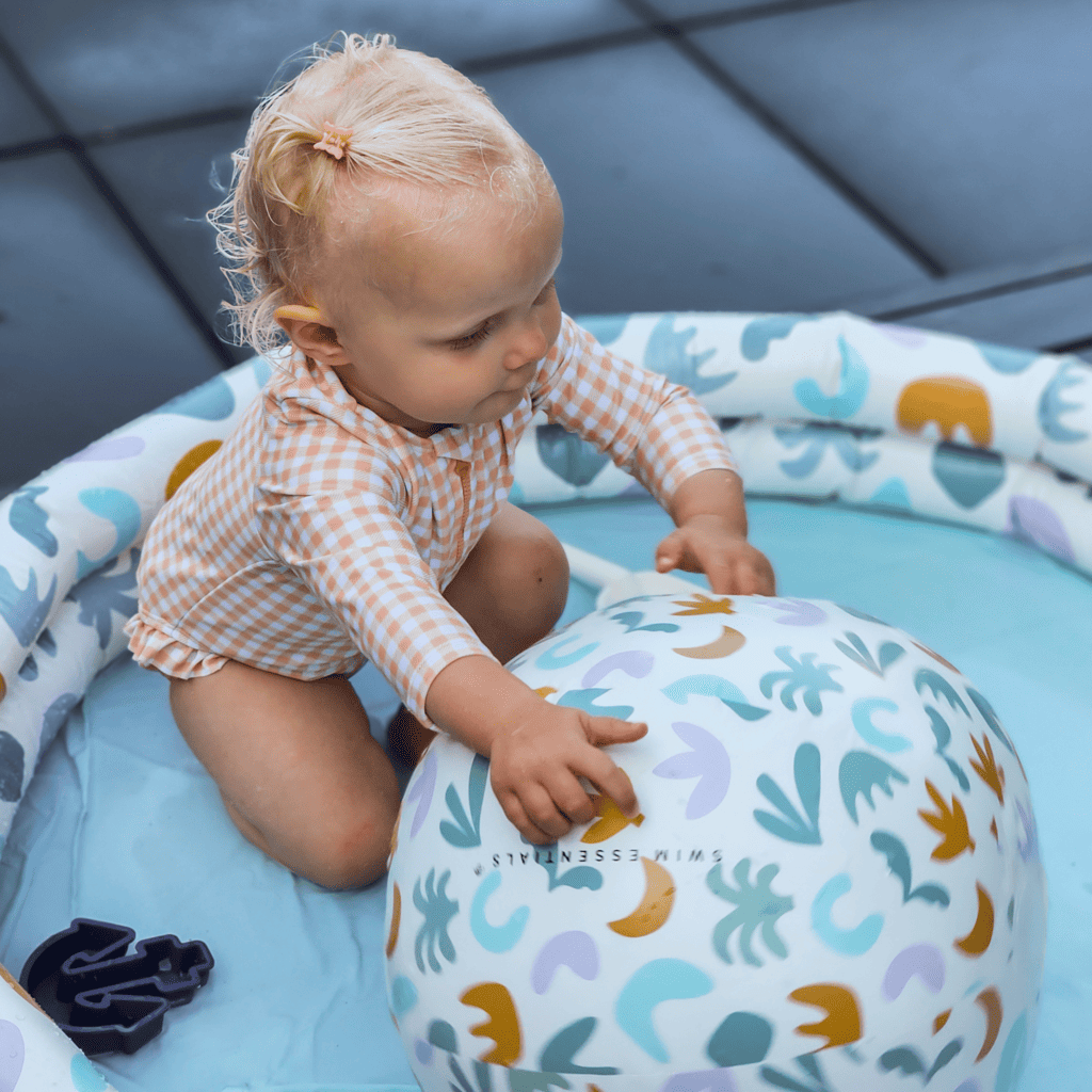 small kid playing in pool with beachball