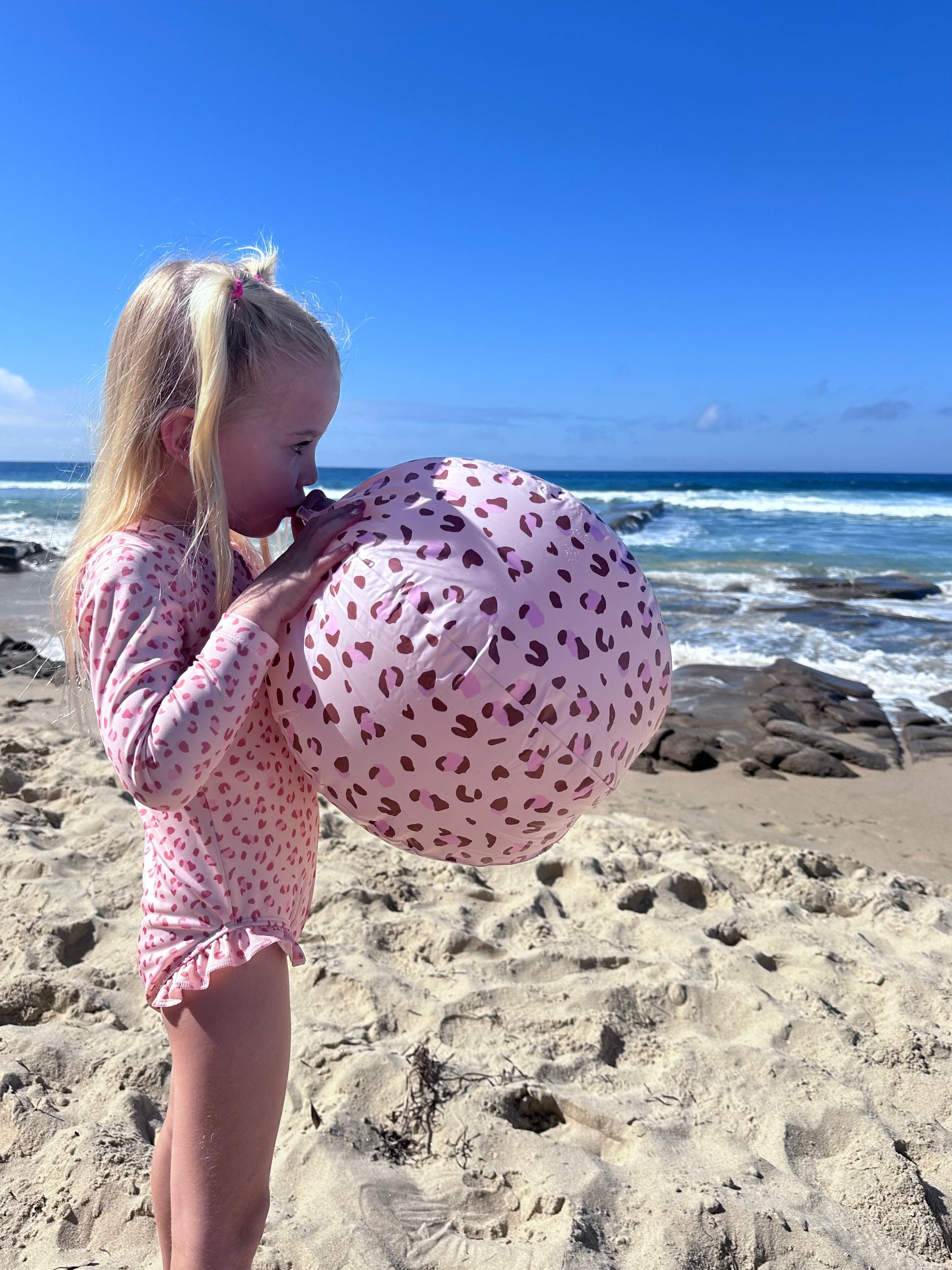 kid blowing up a pink beachball